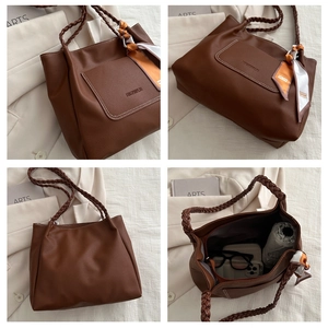 Detail view of brown leather tote featuring woven handles and internal storage capacity