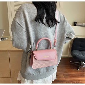 Gros plan du sac bandoulière rose avec texture tressée et logo doré en intérieur
