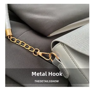 Close-up of golden hardware hook and chain on a silver glitter evening shoulder bag