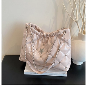 Detail view of pink quilted leather bucket bag with star crystal and metal chain strap