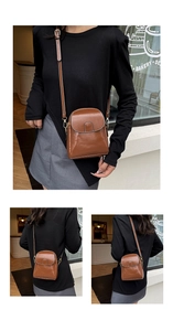 Detail of a brown leather crossbody bag with vintage stitching and gold metal magnetic buckle
