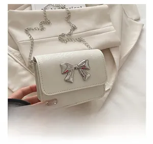 Detail showing creamy white snake-embossed leather texture and silver bow buckle