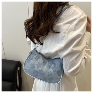 Detailed view of the blue floral jacquard underarm bag on a model wearing white shirt