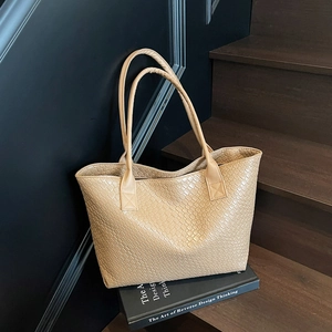 Minimalist beige woven tote bag for women made of premium PU leather on a modern display
