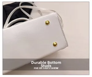 Détails des clous de protection dorés sous un sac fourre-tout en cuir blanc matelassé