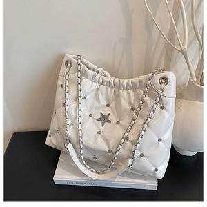 Detail of white quilted bucket bag with star crystal emblem and silver chain straps