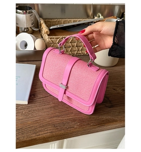 Detail of fuchsia woven fabric texture and leather handle on a chic crossbody bag