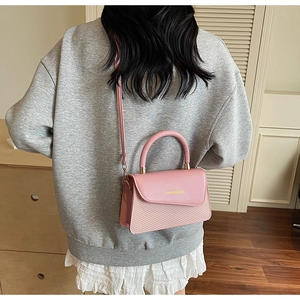 Détail du sac bandoulière rose avec texture tressée et rabat en cuir pour femmes
