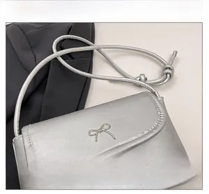 Detail view of silver bow hardware and fine stitching on the stylish square crossbody bag