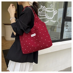 Détail du sac cabas rouge à fleurs avec texture plissée et étiquette Creative Cat