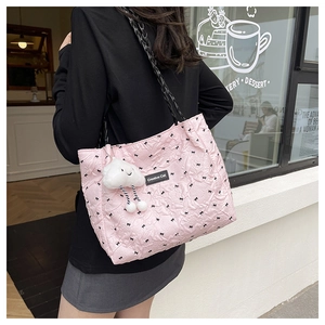 Detailed shot of pink quilted tote bag featuring black bow prints and white plush charm