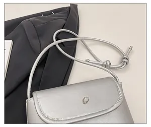 Detail showing the adjustable cord shoulder strap and metallic bow on silver flap bag
