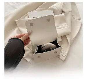 Internal capacity of white leather crossbody bag showing makeup and silver chain