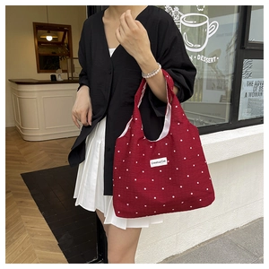 Détail du sac cabas en toile rouge à motif floral avec étiquette Creative Cat et espace