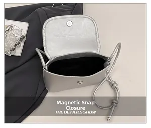 Detail shot of silver matte crossbody bag with magnetic buckle closure and black lining