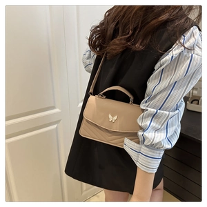 Detail of crossbody bag with butterfly clasp, V-quilted texture and thin shoulder strap