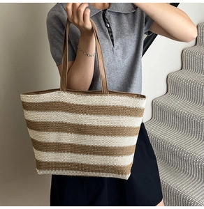 Detail view of woven tote bag with brown and cream stripes worn over the shoulder