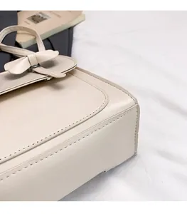 Detail of cream leather handbag with decorative bow and Fashion lettering embroidery