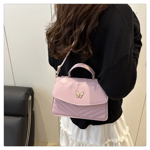 Detail of light purple crossbody bag with butterfly clasp and V-quilted texture on shoulder