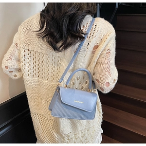 Vue arrière d'un sac bandoulière bleu clair texturé porté par un mannequin en décor épuré