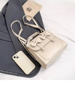 Detail of cream PU backpack with bow accents, pearls, and 'FASHION' text on a gray blazer