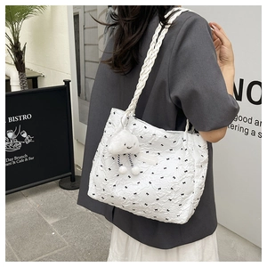 Close-up of white quilted tote bag featuring black bows and a cloud plush charm