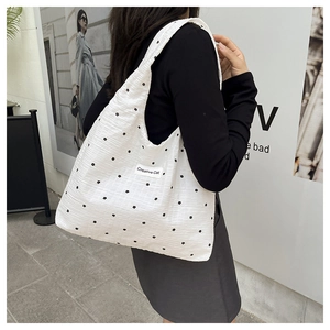 Détail du sac cabas en toile blanche avec broderies de fleurs noires et texture gaufrée