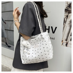 Detail of white pleated tote bag featuring black bow patterns and cute plush cloud charm