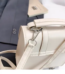 Detail of silver metal hook and fine stitching on a beige PU leather handbag