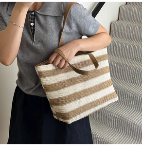 Dettaglio della borsa tote a righe con spalline in pelle marrone e trama in paglia intrecciata