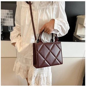 Détails du motif matelassé sur le sac fourre-tout bordeaux dans un décor de style de vie