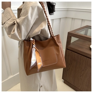 Detail of caramel tote bag showing lychee grain leather texture and woven handle with scarf