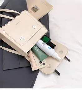 Detail view of the spacious interior of a beige leather crossbody bag with items