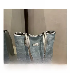 Detail of light blue denim tote bag with silver glitter and metal logo tag