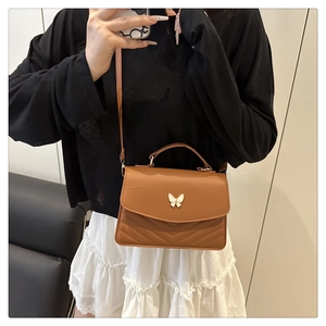 Detail of caramel leather square crossbody bag with 3D white butterfly hardware