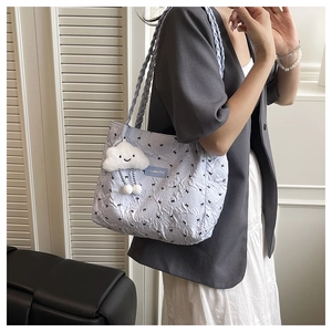 Light blue quilted tote bag with black bows, woven strap, and cloud plush charm