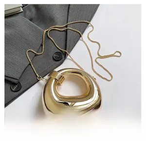 Macro view of gold crescent acrylic evening bag with fluid metal texture and chain