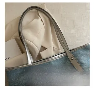 Detail of blue denim tote bag with silver sequins and metallic leather handle attachments
