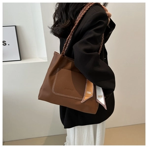 Close-up of brown litchi pattern leather tote bag with contrast stitching and silk scarf