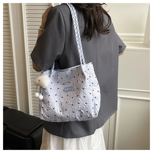 Detail of light blue quilted tote bag with black bows and plush cloud pendant