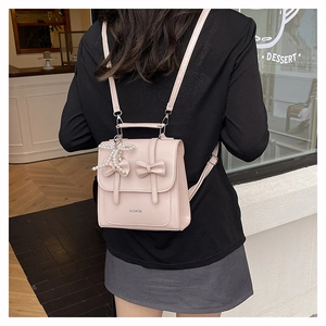 Rear view of a light pink mini backpack with bow accents and pearl charm decoration