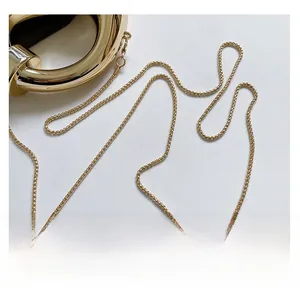 Detail of high-polish gold round handle and fine chain strap on a crescent bag