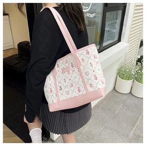 Detail of cute tote bag featuring pink bear prints and leather straps in a cafe setting