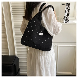 Détail d'un sac cabas en toile noire avec motif floral blanc et écusson tissé
