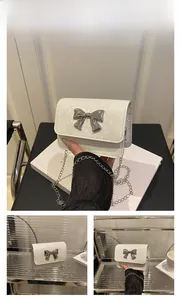 Detail of white crocodile texture mini bag with silver bow clasp and chain strap