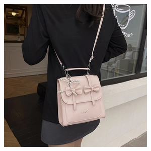 Close-up of light pink PU leather bag with bow knots and pearl butterfly pendant charm