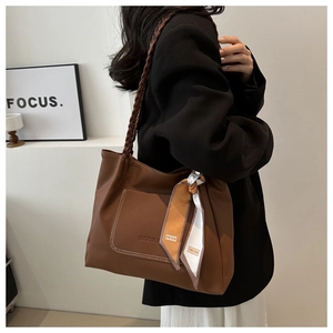 Detail of a brown lychee grain tote bag with braided strap and silk scarf accessory