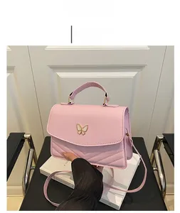 Pink crossbody bag with gold butterfly clasp and quilted V-pattern on the front flap