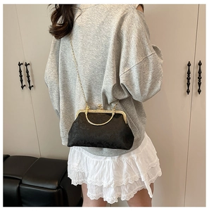 Détail d'un sac jacquard noir vintage avec fermoir à baiser et chaîne dorée sur modèle