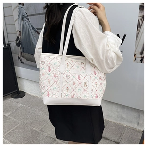 Detail of a large capacity white tote bag with cute cartoon prints on a shoulder strap